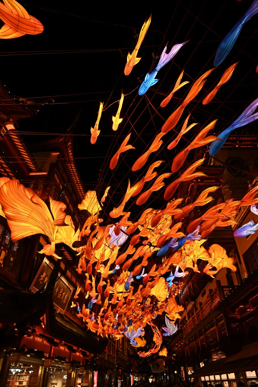 A stream of illuminated fish lanterns suspended above visitors at the Yuyuan Lantern Festival