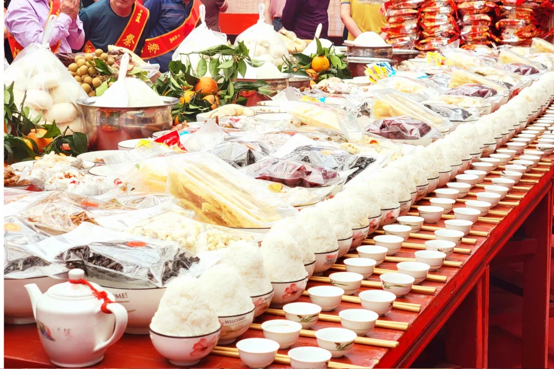 Rice bowls, tea cups, fruit and prepared dishes arranged on a Qingming ancestral-hall table