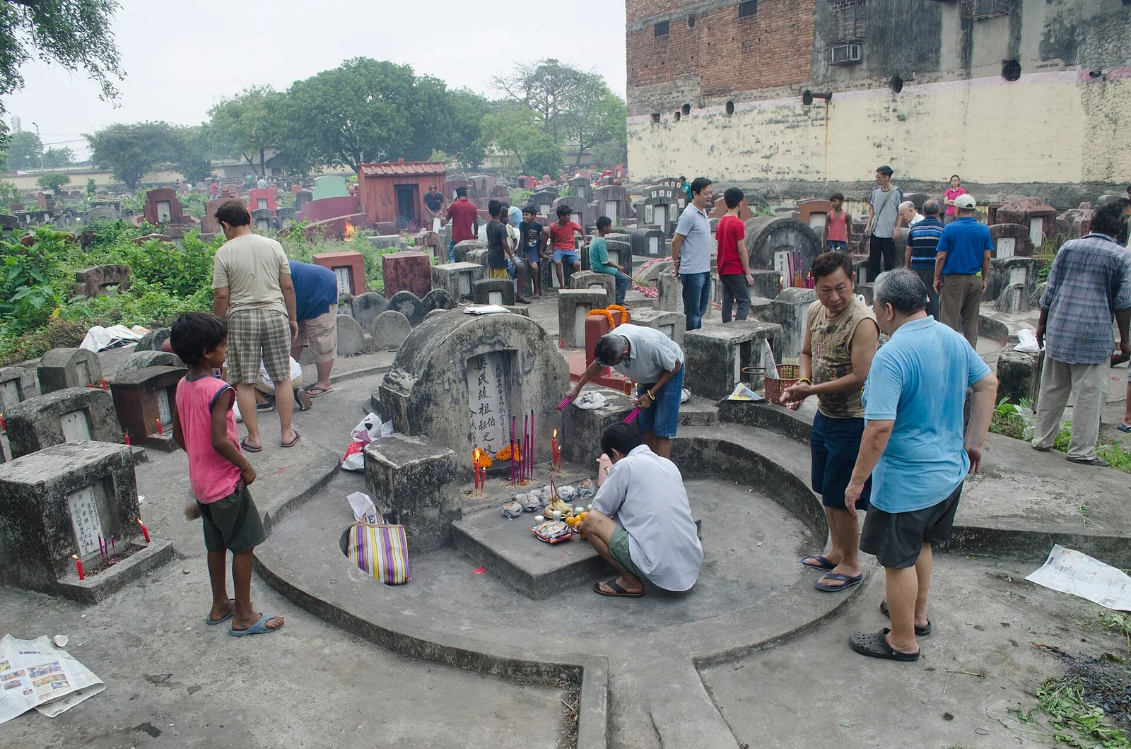 Adults and children tending graves and arranging offerings at Chonghe Dong Cemetery during Qingming