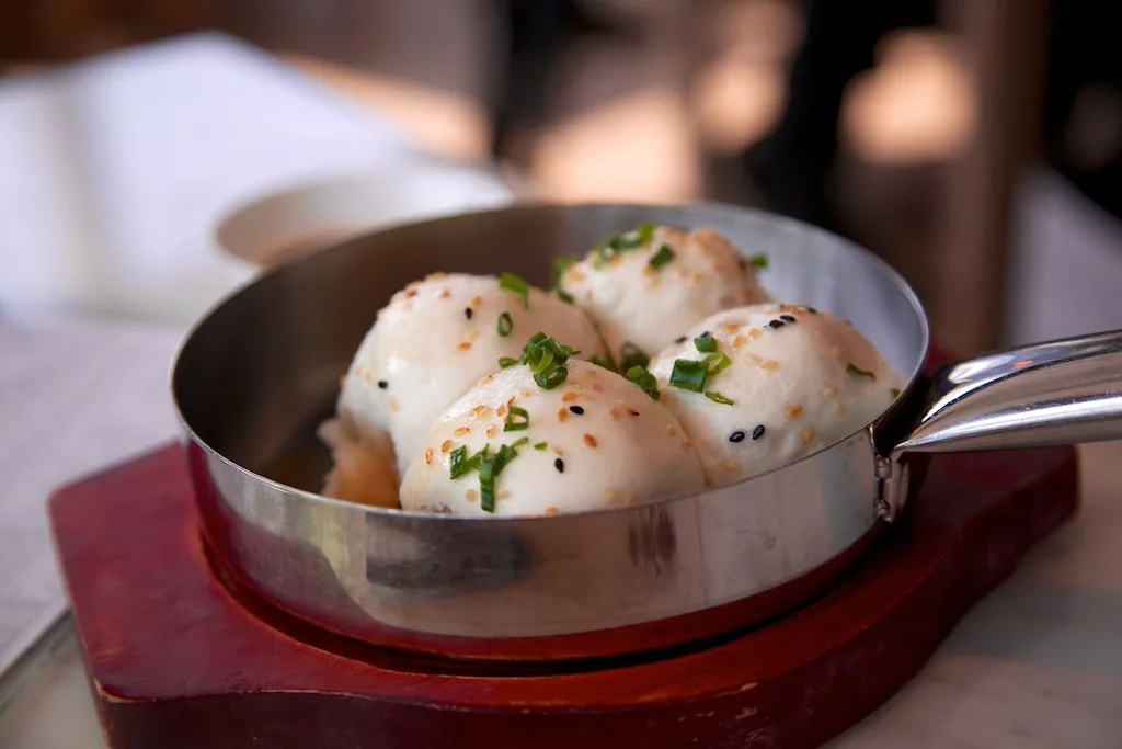 Baozi variation shengjian mantou cooking together in a wide pan