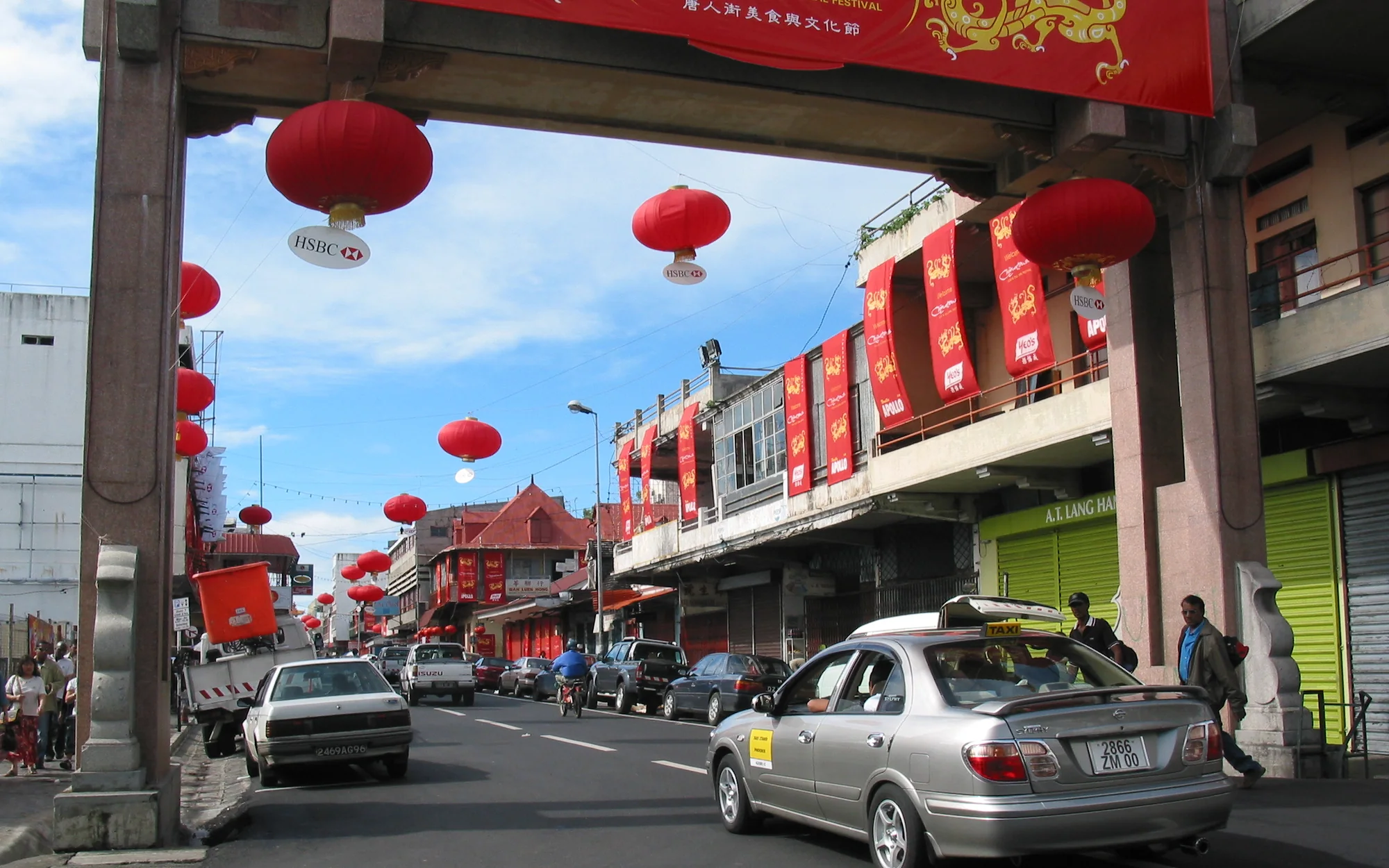 Port Louis Chinatown gate, shopfronts and street traffic in Mauritius beneath red festival lanterns