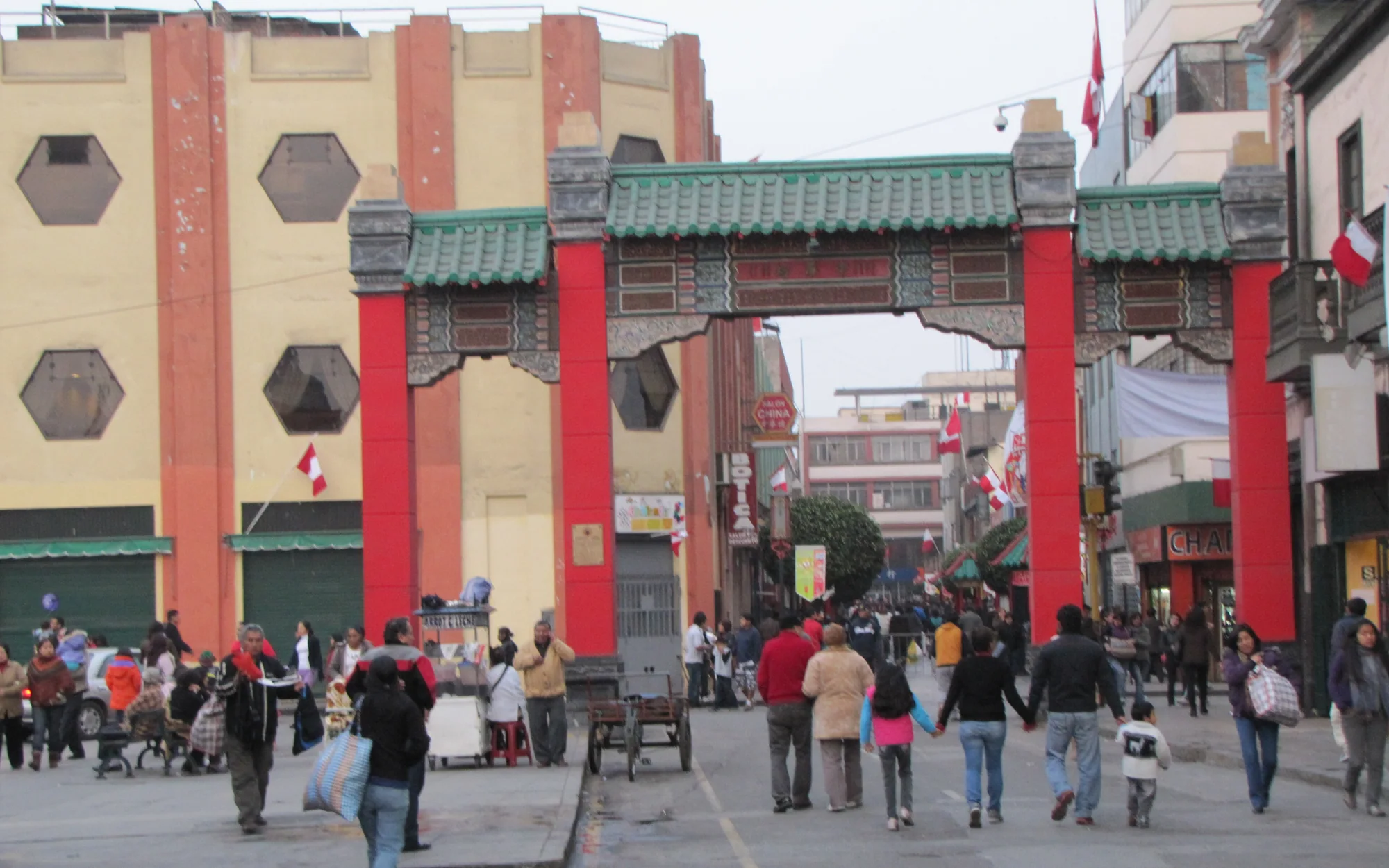 Calle Capón's Chinatown gate, Peruvian flags, vendors and families in central Lima