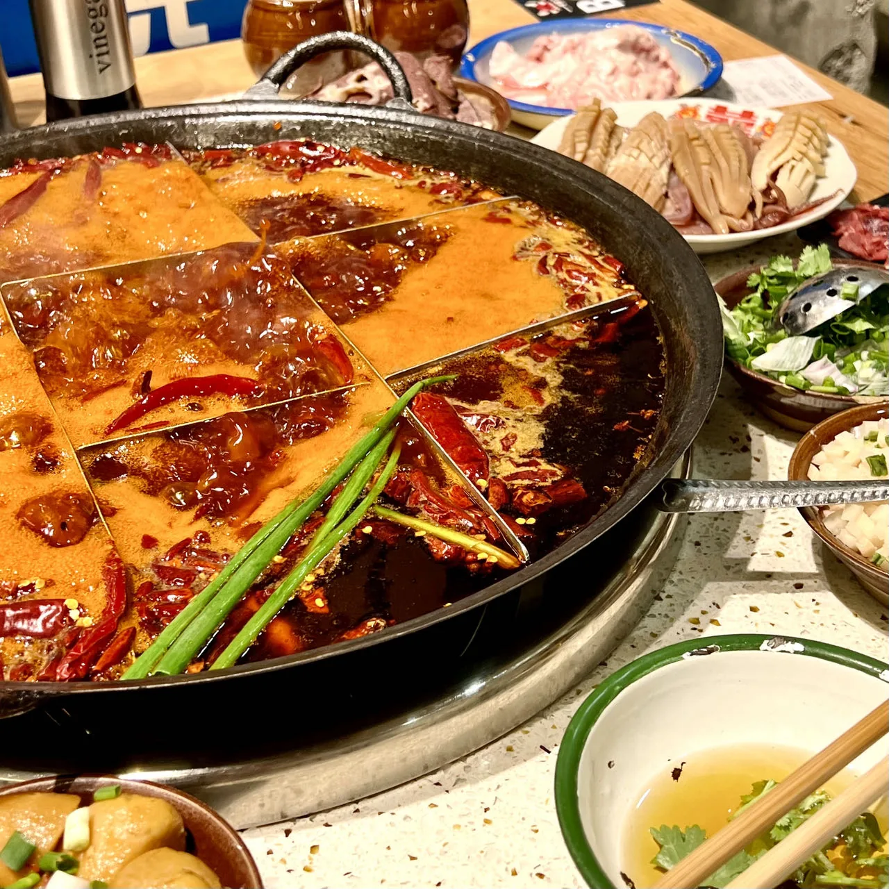 Chinese hot pot in the Chongqing nine-grid style surrounded by vegetables, tofu and meat