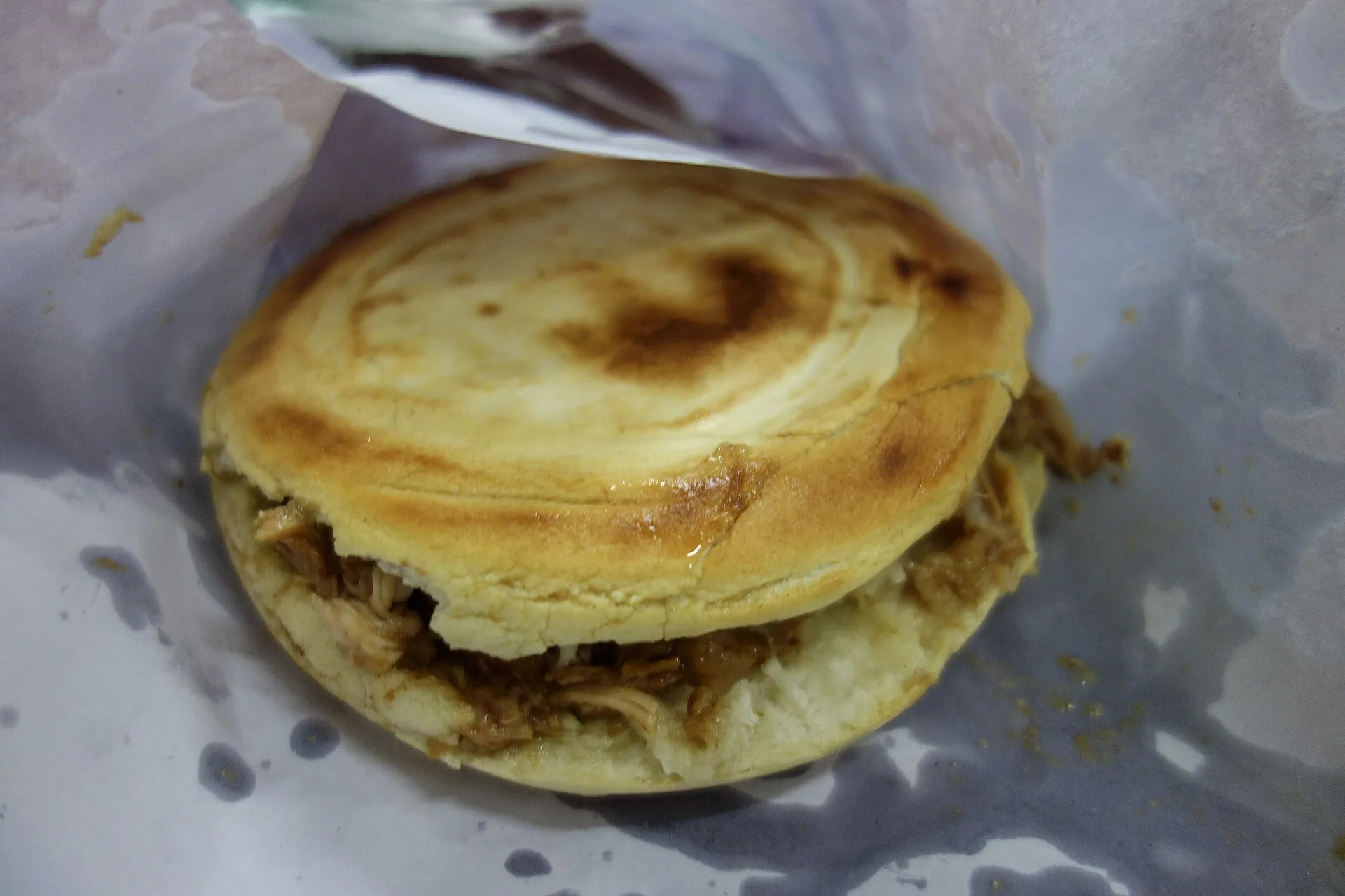 Chinese street food shown as a Xi'an roujiamo filled with braised meat