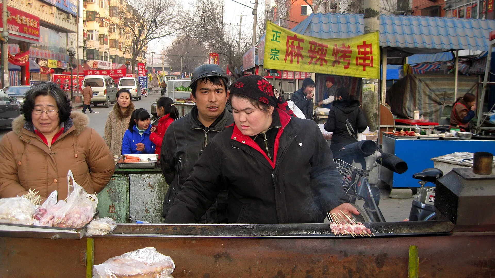 Chinese street food vendors preparing mutton skewers on a griddle in Tianjin