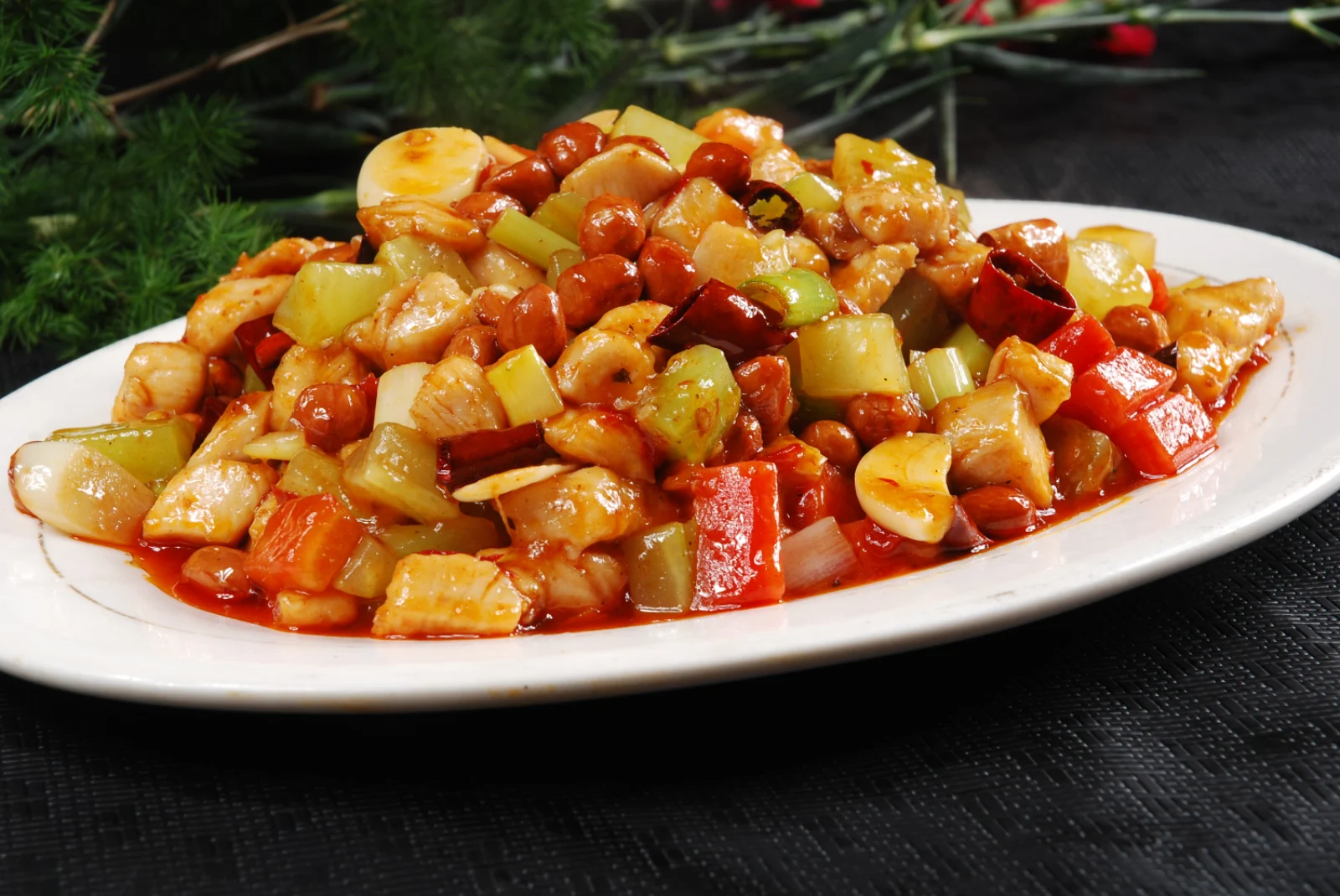 A close view of Kung Pao chicken showing diced chicken, peanuts and dried chilies