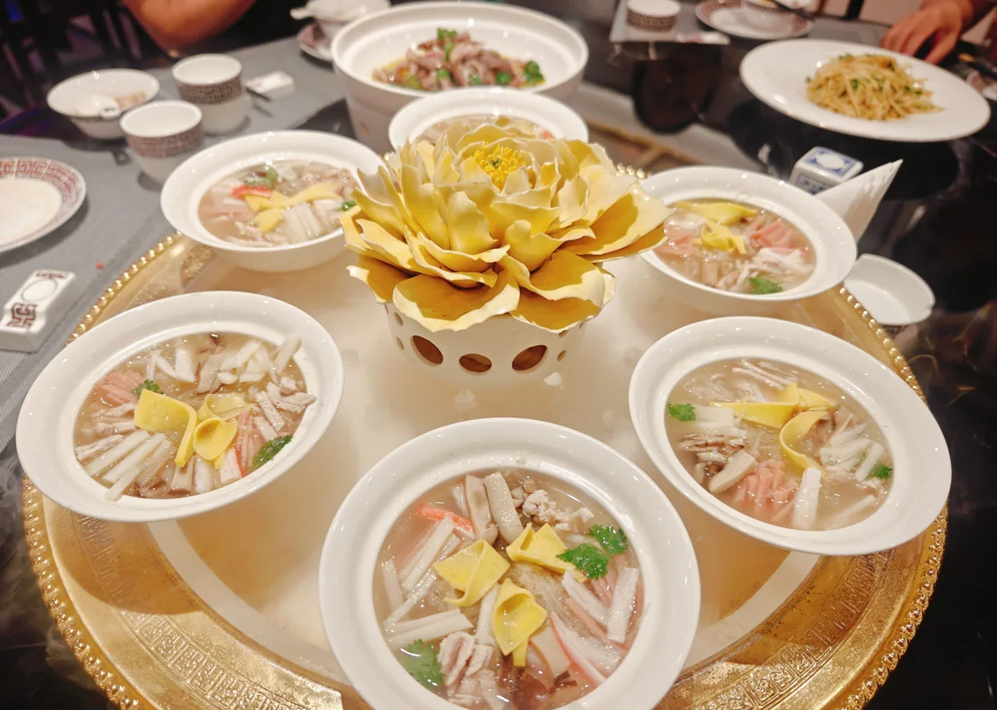Real restaurant presentation with a flower centerpiece and several small bowls arranged around it at a Luoyang Water Banquet