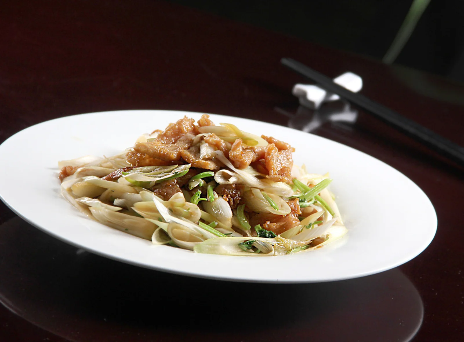 Beijing food shown through scallion stir-fried lamb on a white plate