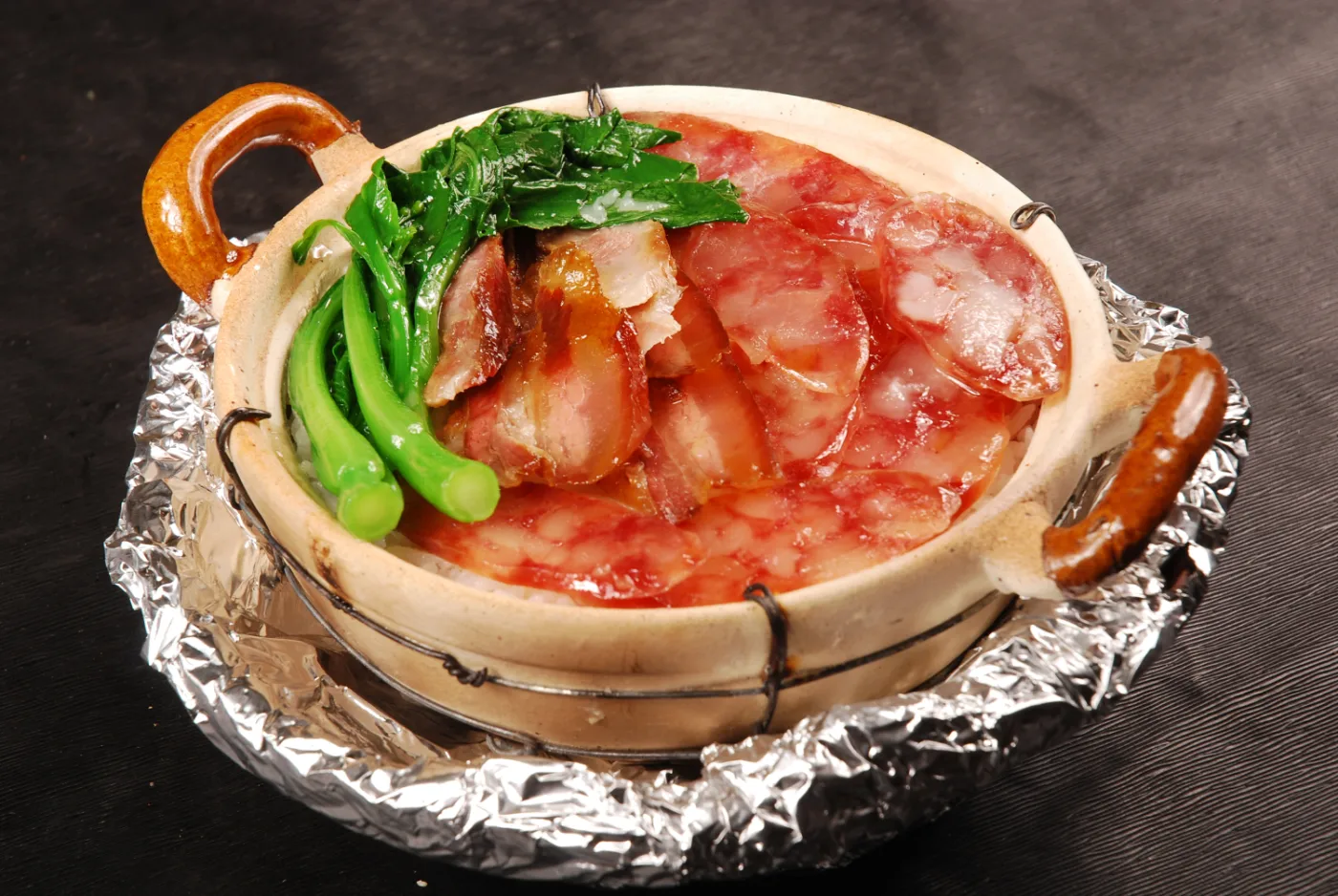 Cantonese clay-pot rice topped with cured sausage, roast meat and greens