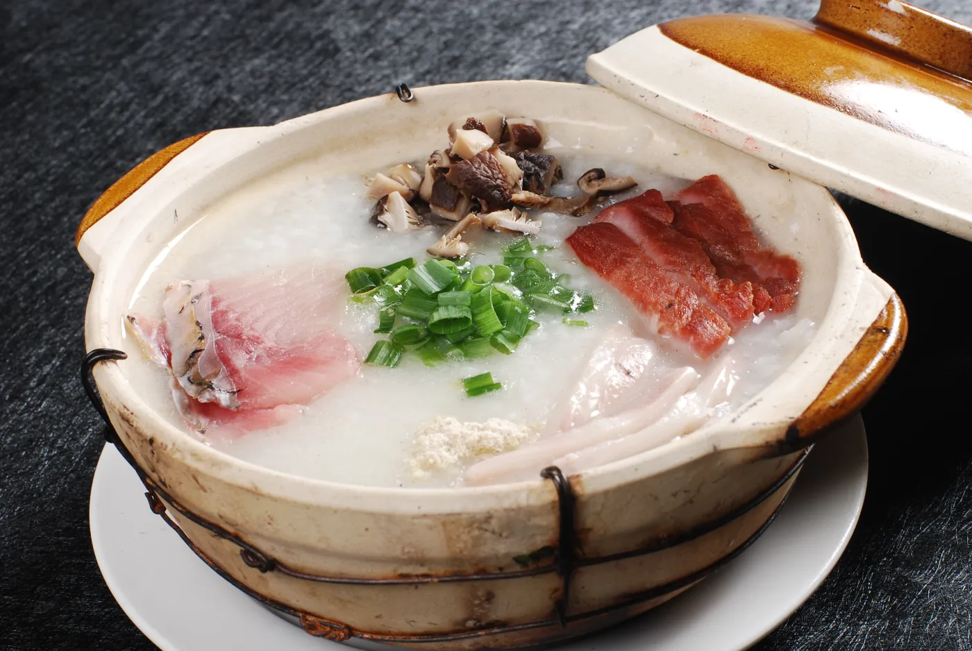 Liwan-style sampan congee with fish, meat and scallion in a clay pot