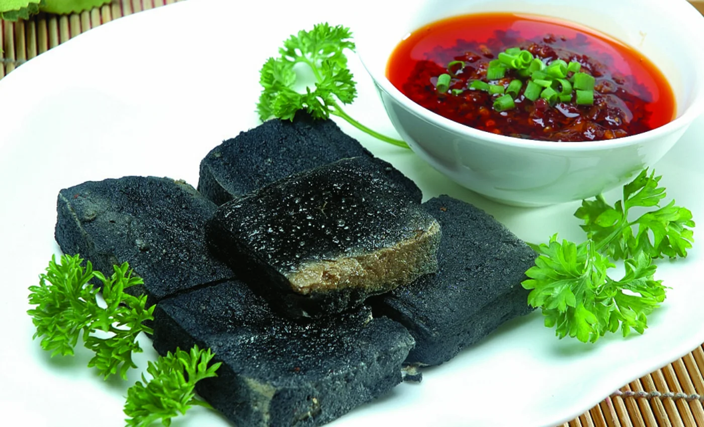 Black Changsha-style stinky tofu with red chili sauce, the city's famous snack treated as food rather than a dare