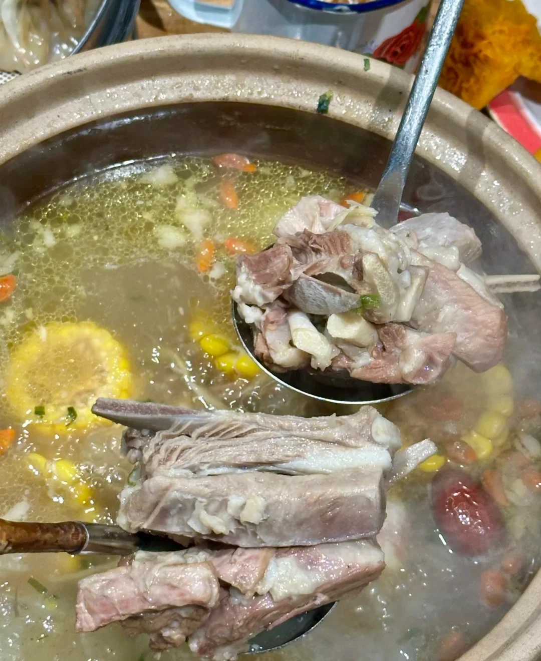 A real Zhengzhou lamb pot with bone-in meat lifted above a clear broth