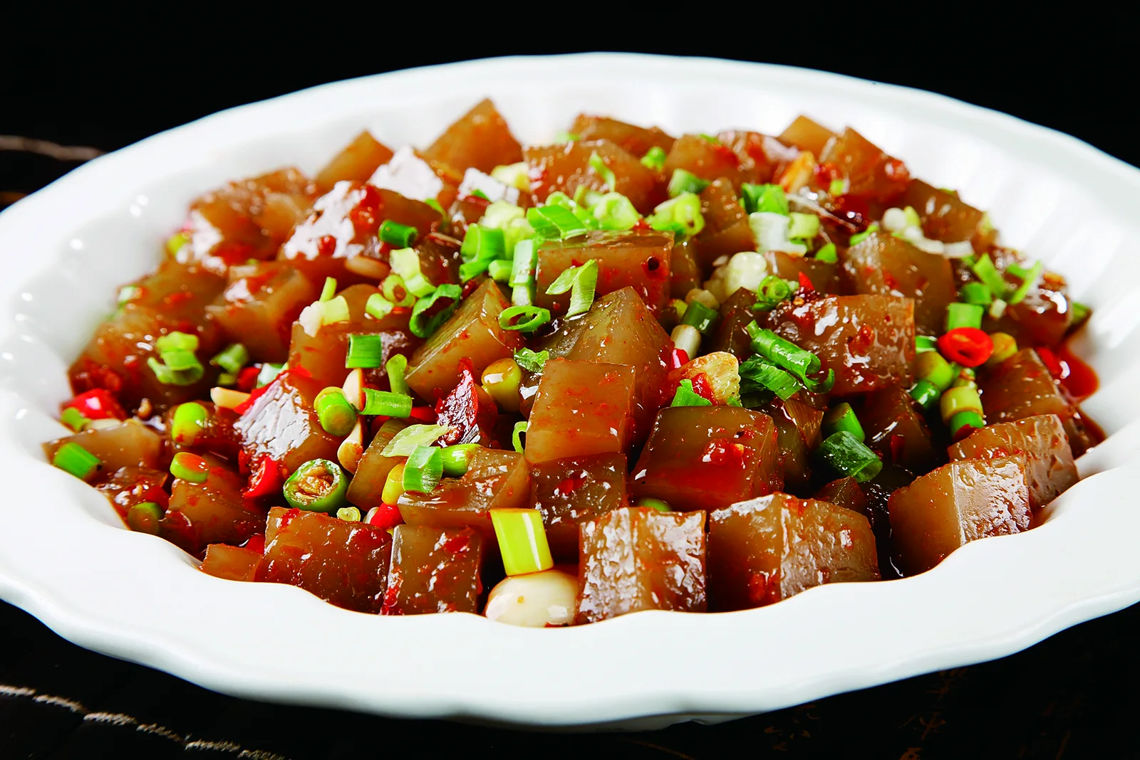 Dark translucent pieces of fried liangfen with scallion, garlic and chile