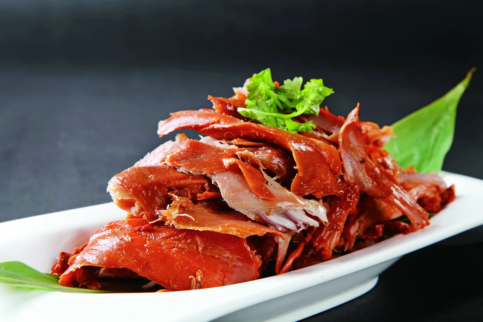 Glossy torn rabbit meat arranged on a white platter