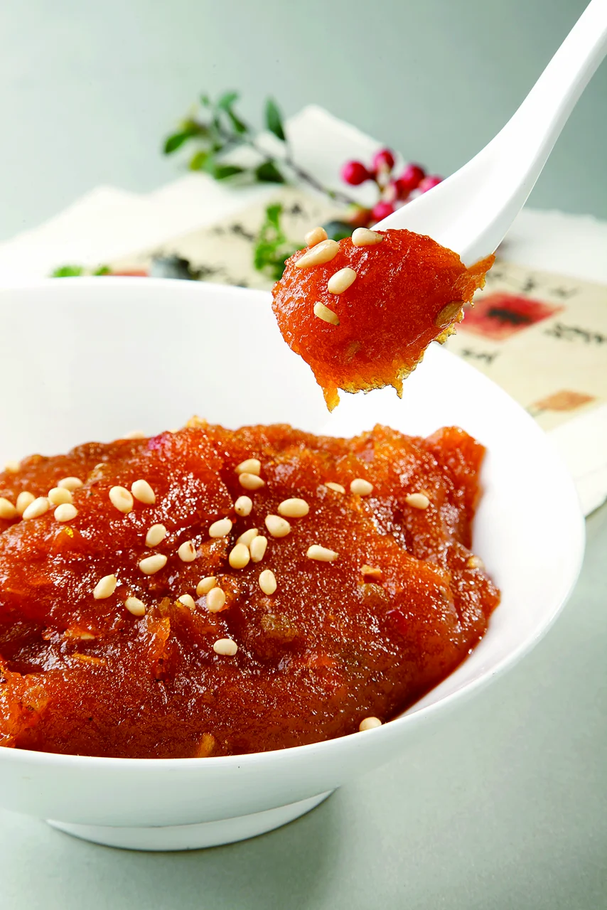 Glossy red-orange sweet potato puree topped with white sesame seeds