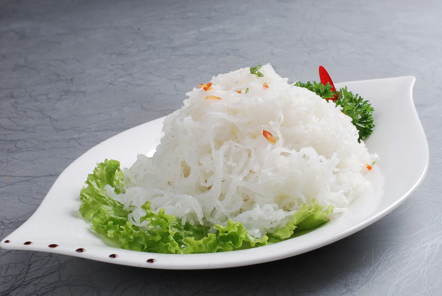 Finely cut white radish arranged as Luoyang peony yan cai on a white platter