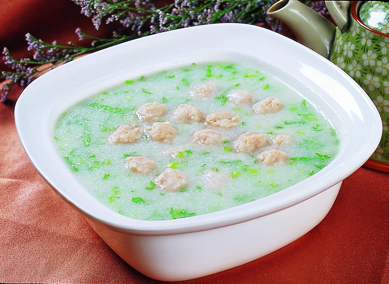 Freshly poached meatballs in a light green-speckled broth