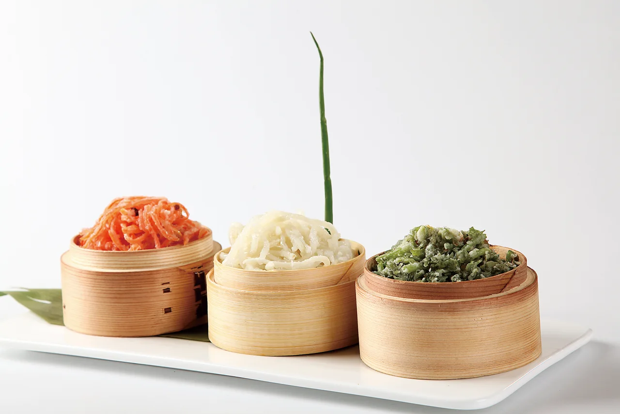Three colors of steamed vegetables served in small bamboo containers