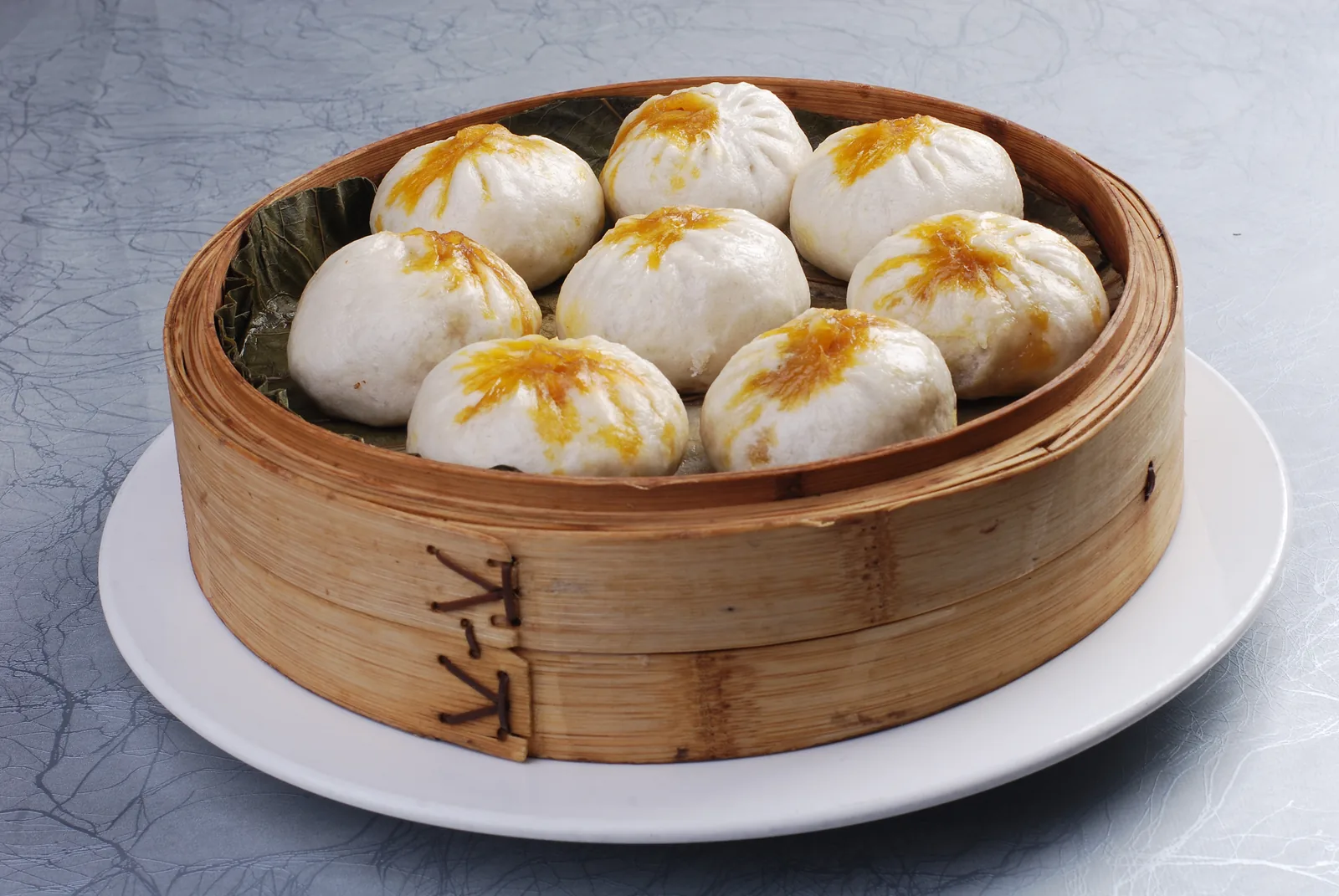Crab-roe-colored soup buns in a bamboo steamer, representing a rich restaurant version