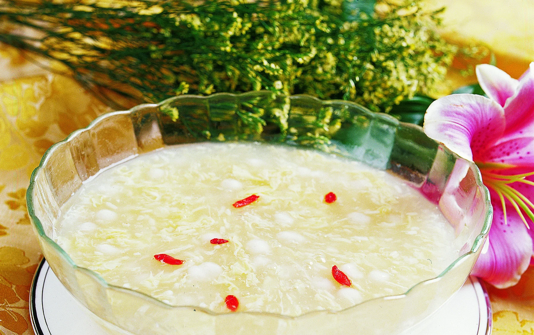 Small glutinous-rice balls suspended in a pale fermented-rice sweet soup with red goji berries