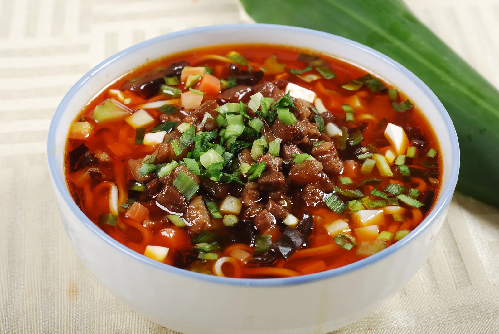 Qishan-style saozi noodles in a red sour broth with finely cut toppings