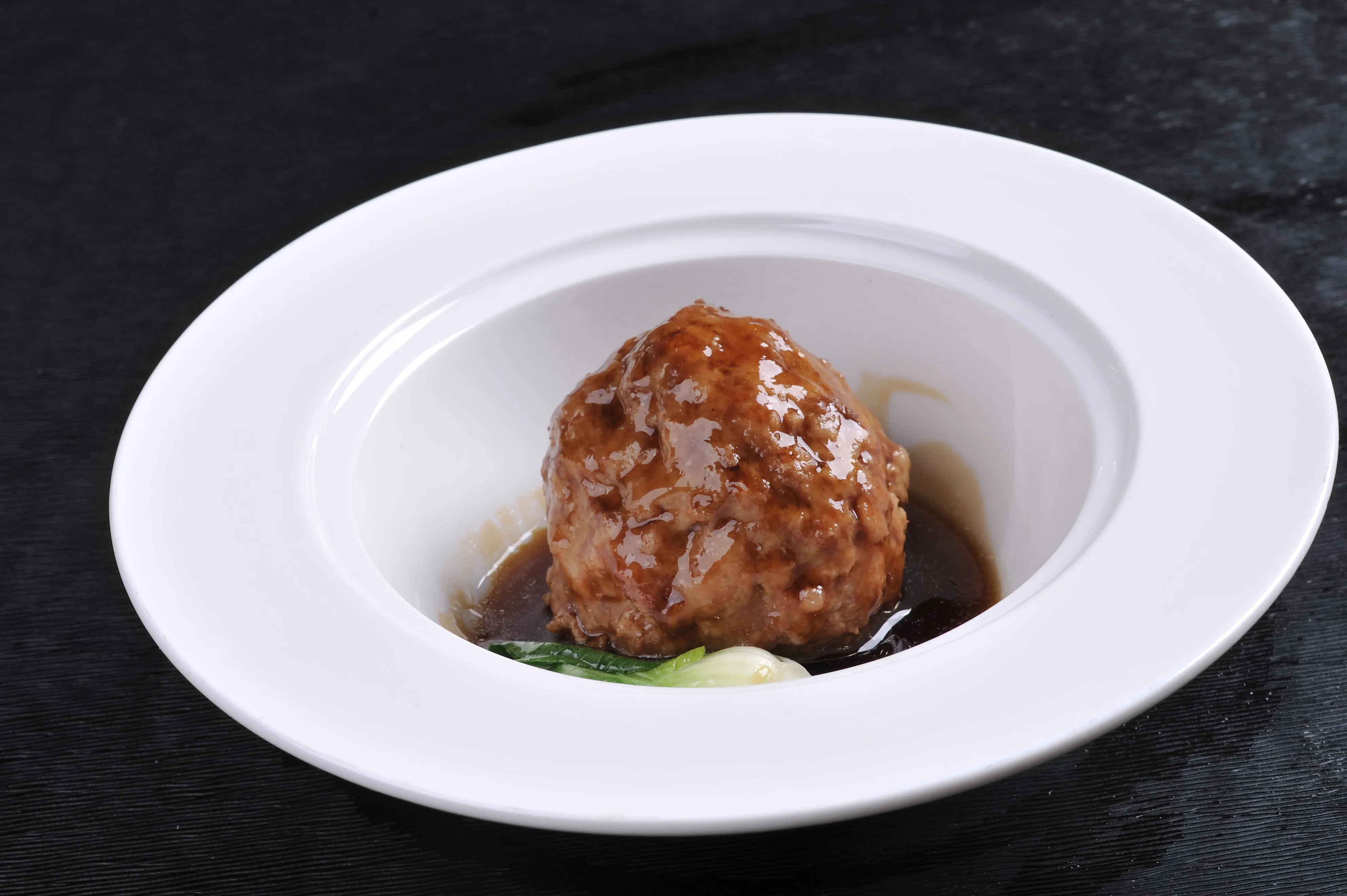 A large tender Yangzhou-style lion's head meatball served in braising liquid