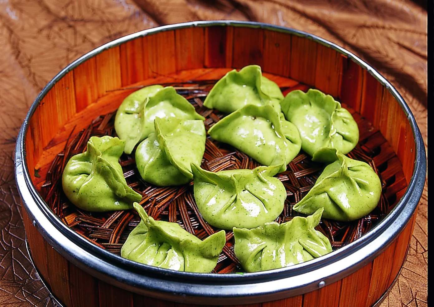 Green vegetable dumplings arranged as a shared steamed course, showing why color alone cannot prove a filling is vegetarian