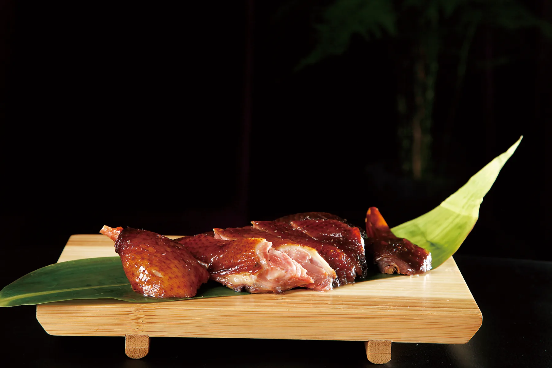Hangzhou soy duck cut into pieces on a bamboo board