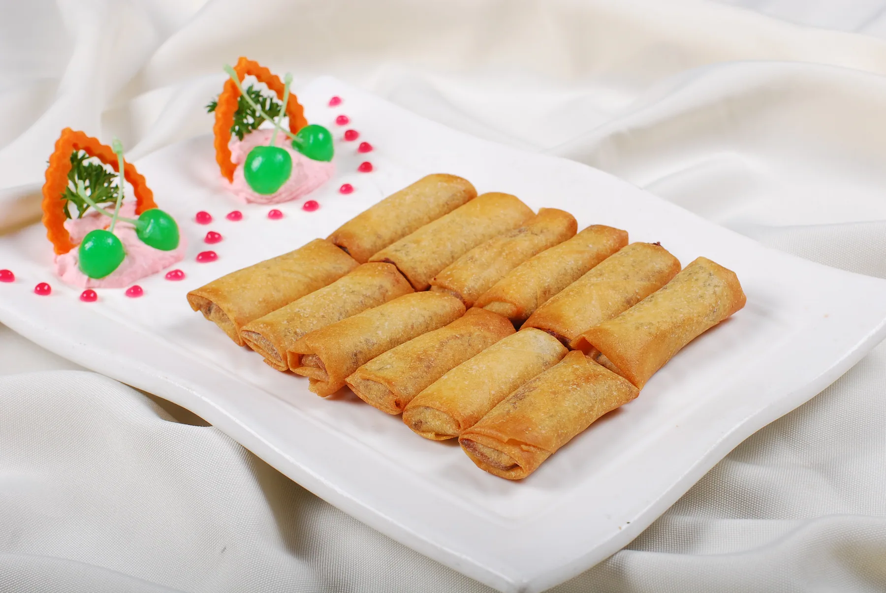 A real plate of small Chinese spring rolls with thin sealed wrappers fried to uneven golden brown