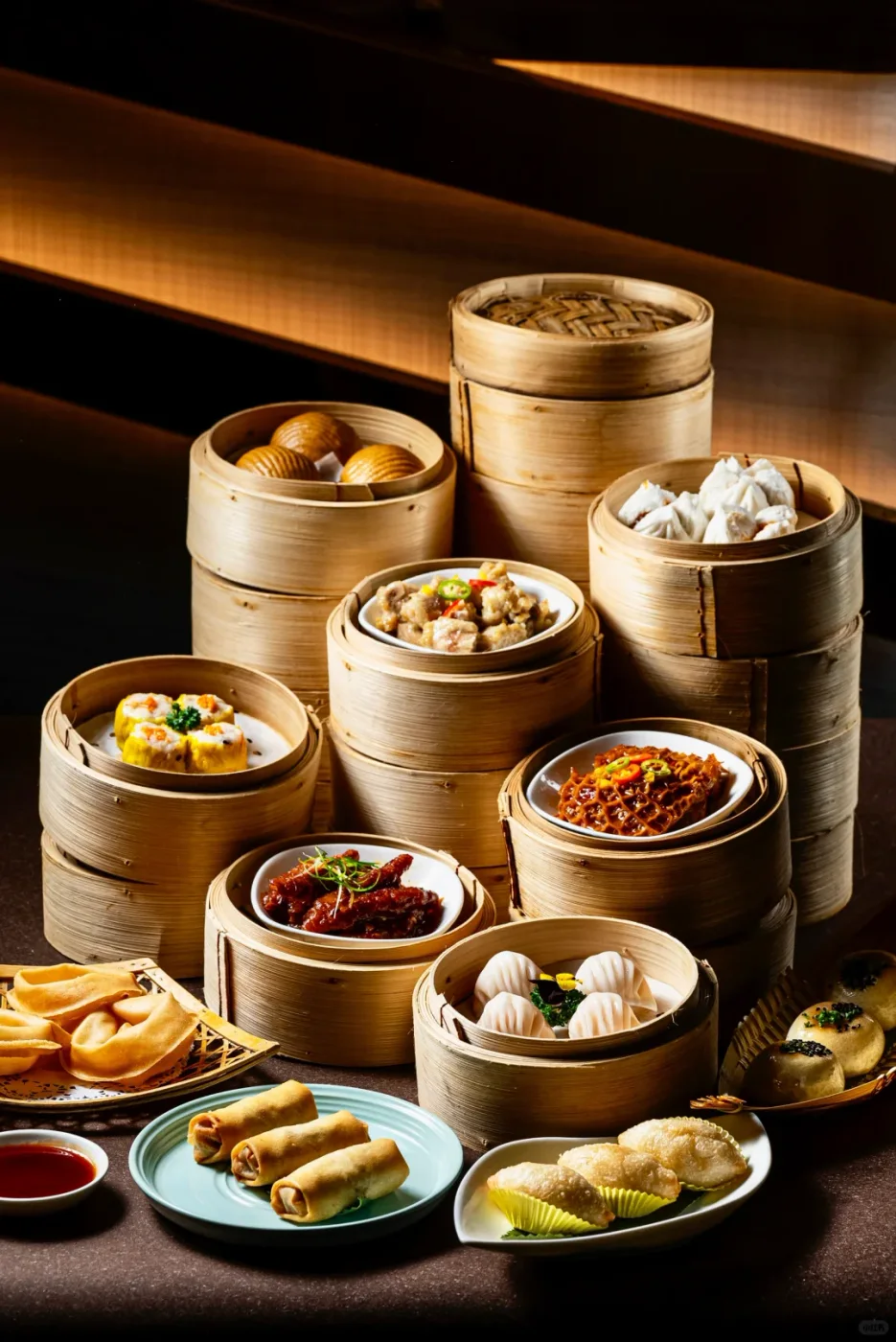 Whole fried spring rolls sit among har gow, buns and other dishes on a real yum-cha table