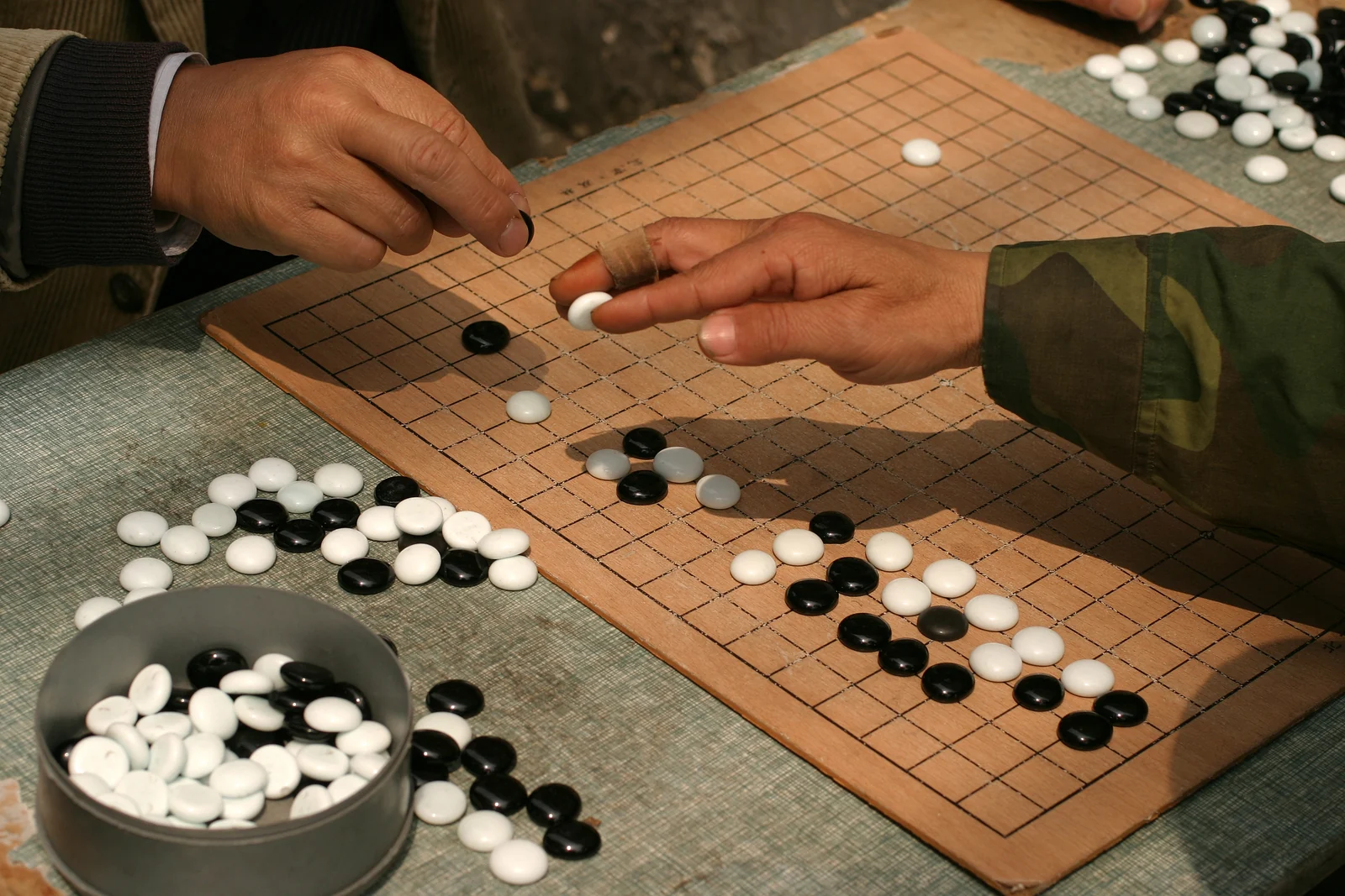 Two people placing black and white stones during a real weiqi game in Shanghai