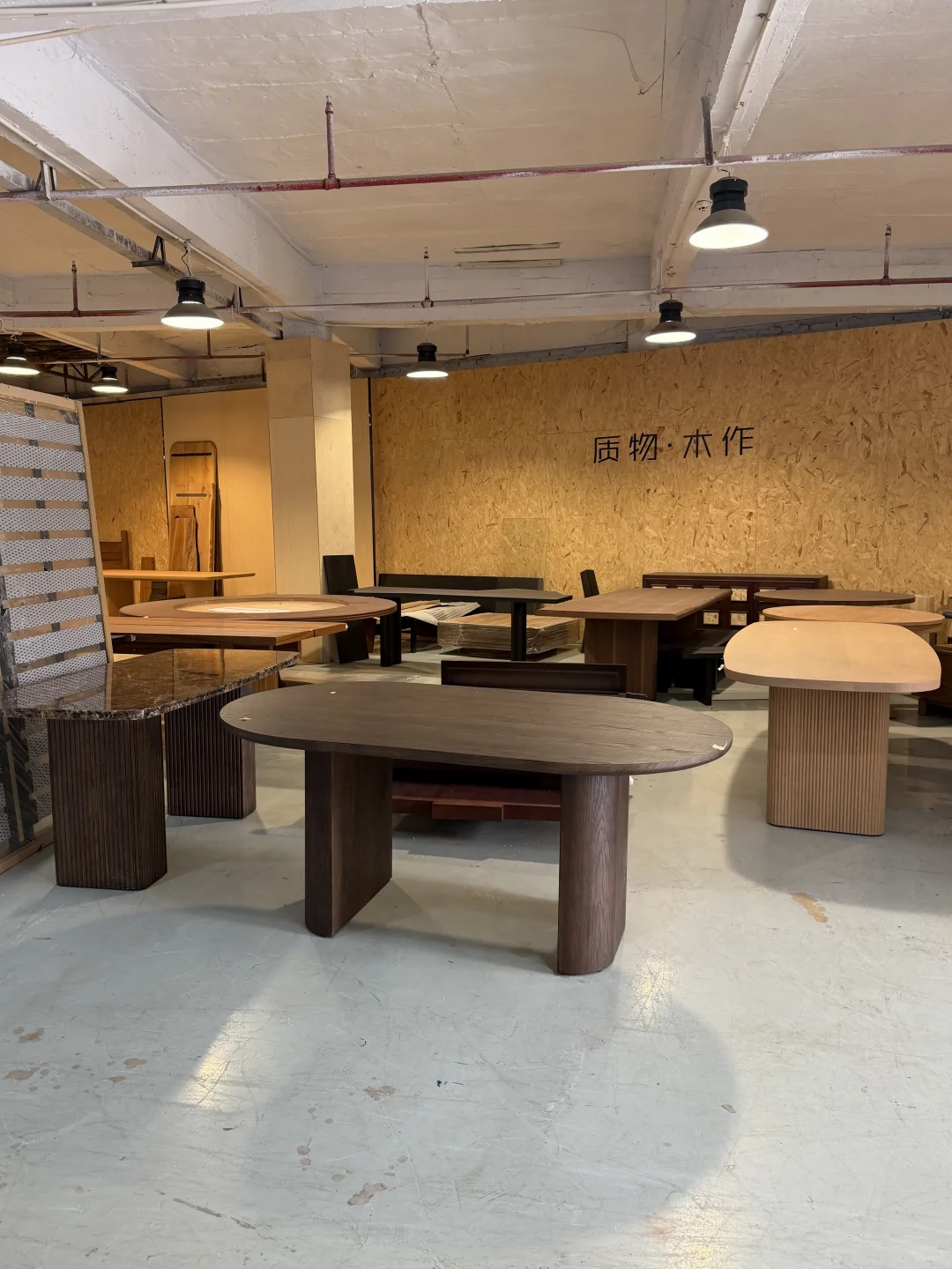 A showroom of wood-toned tables allows direct comparison of top shapes, base proportions and finish colors
