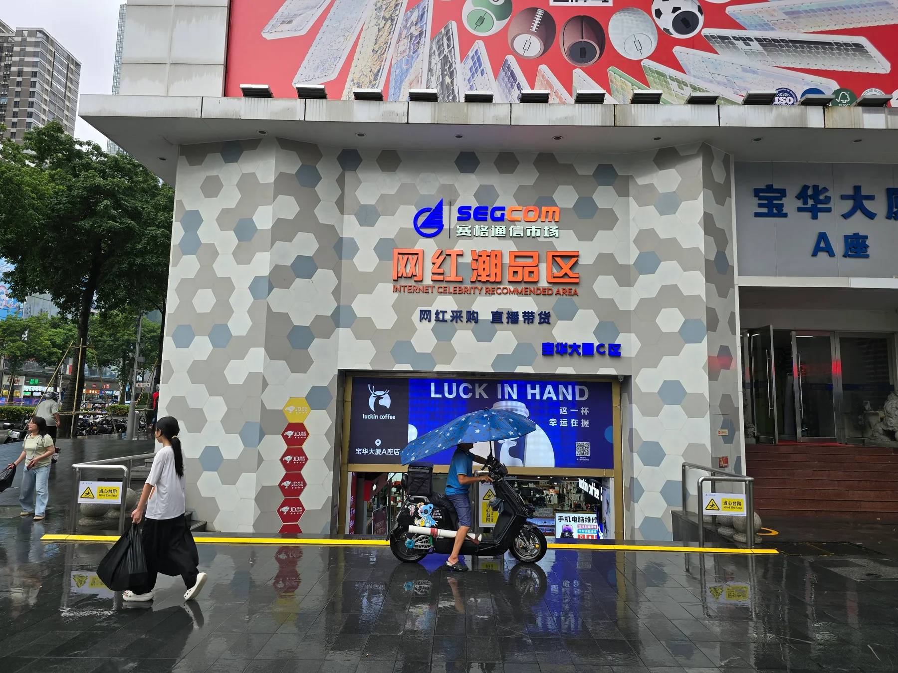SEGCOM communications market entrance in Huaqiangbei with a sign advertising trending products, photographed in 2025