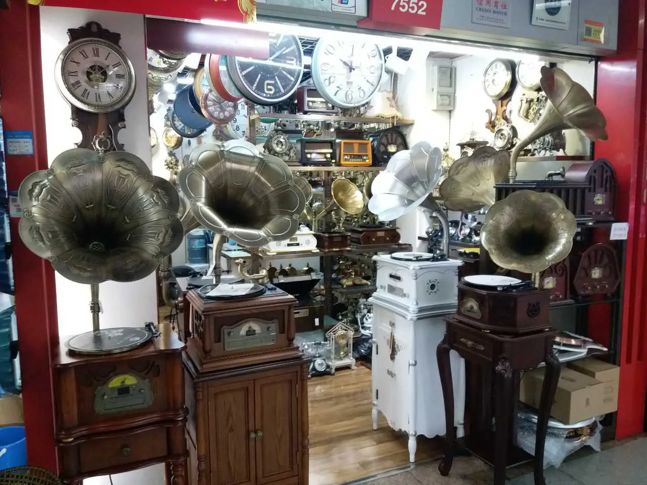 Horn-shaped gramophone displays with different cabinets, finishes and sizes beside clocks in a Yiwu District 1 shop