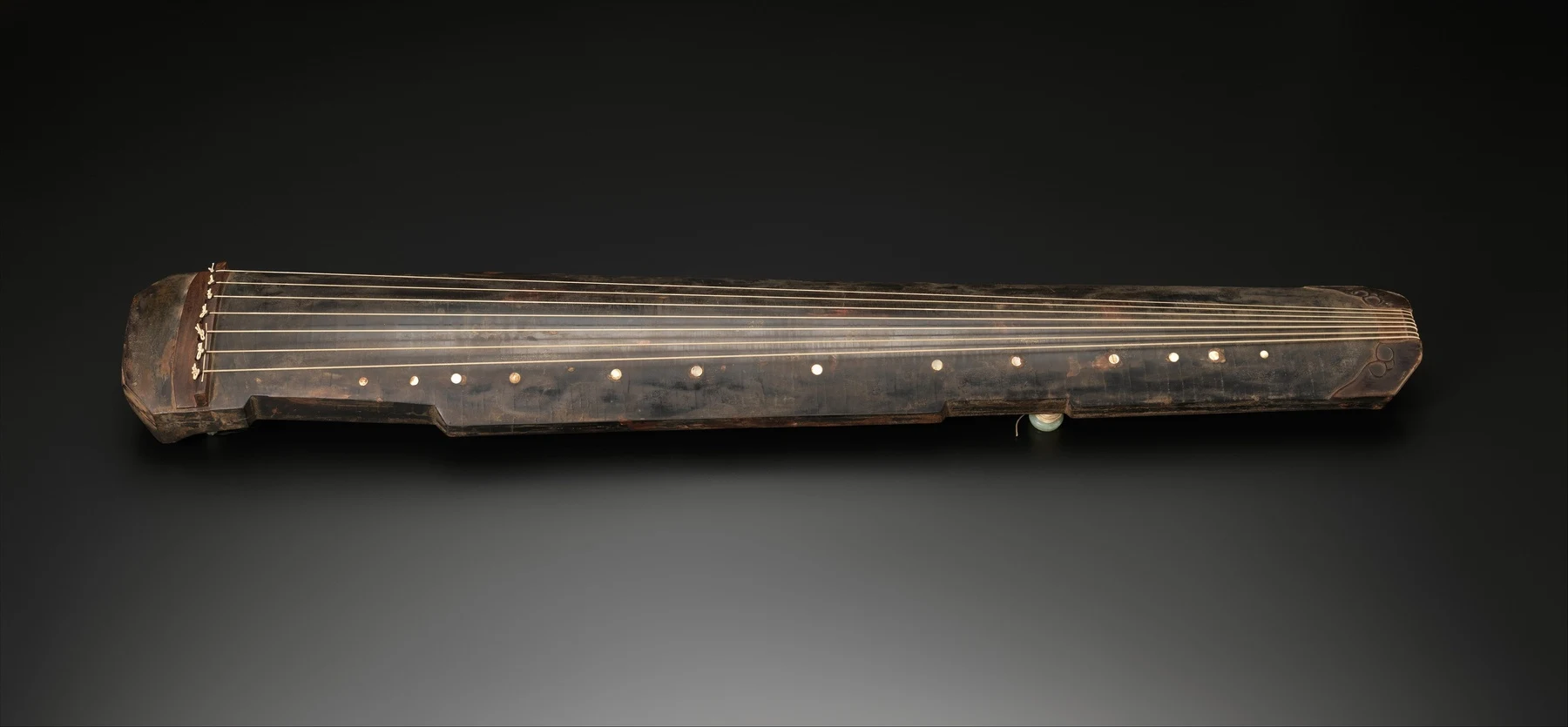 A qin dated 1634, photographed as a complete instrument with strings running along its body