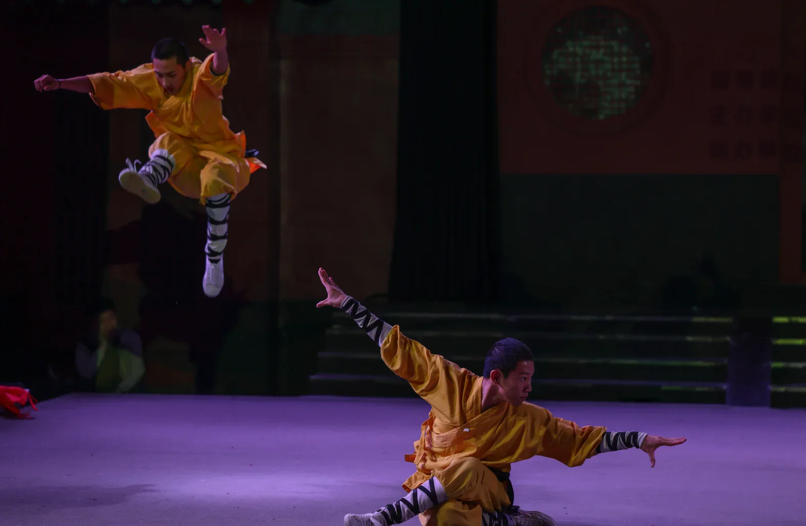 Two Shaolin performers holding sharply different levels in one public acrobatic sequence