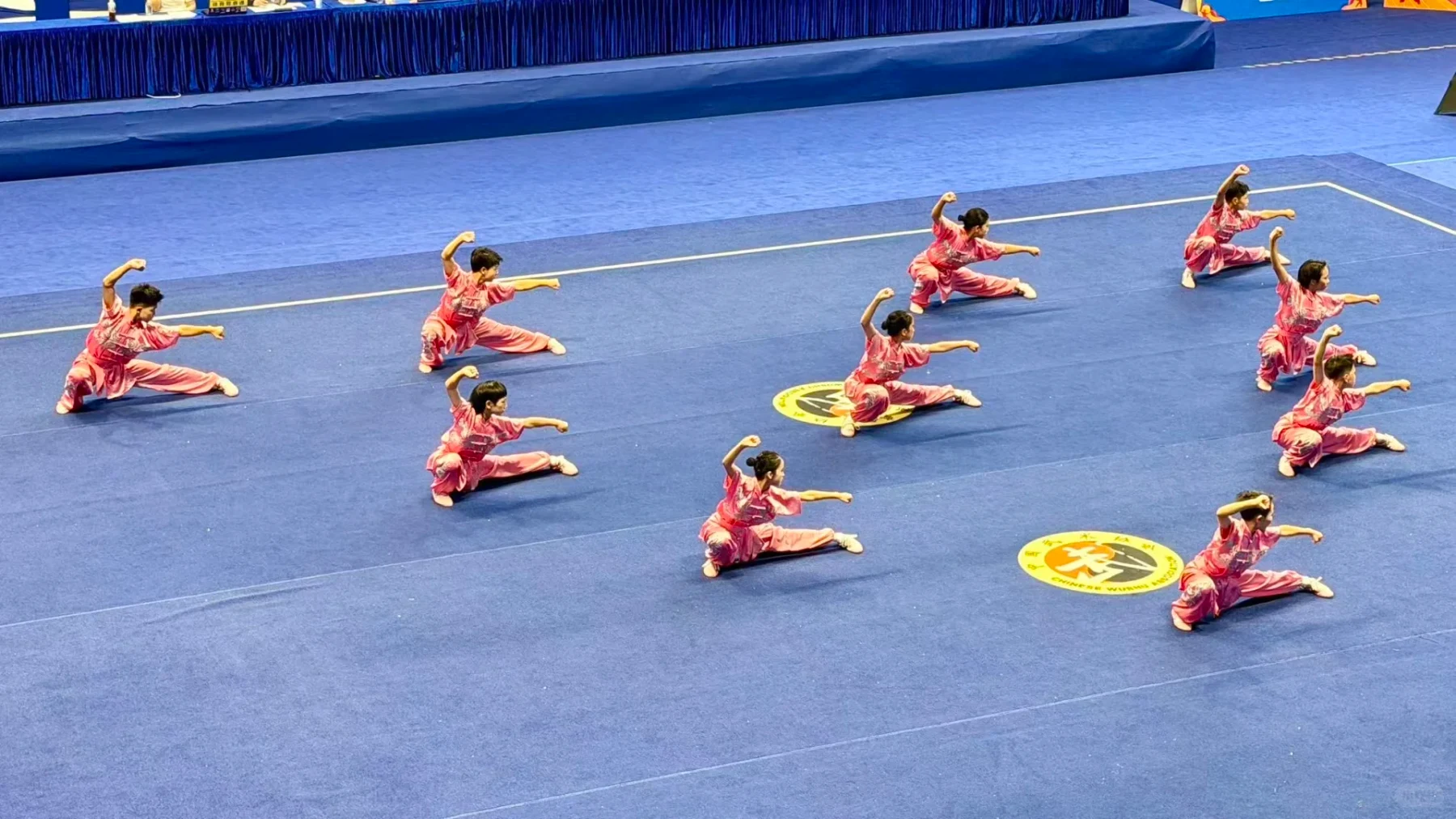 The same school wushu team later dropping into a coordinated low ground formation