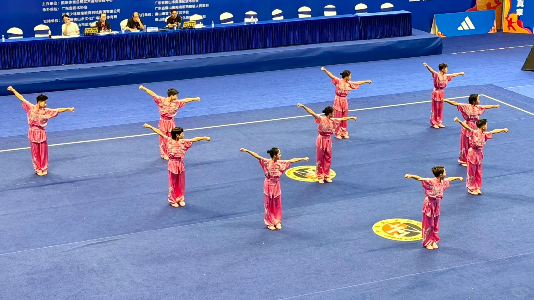 A school wushu team opening its competition sequence in a broad standing formation