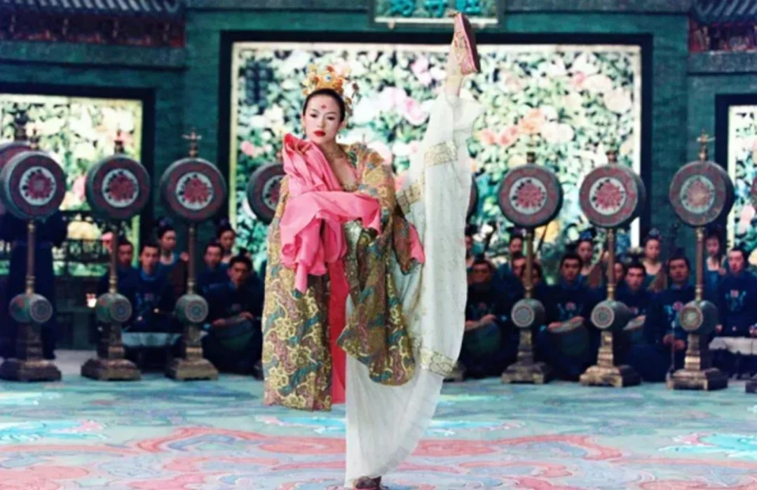 Mei balances inside the Peony Pavilion while musicians and painted drums form a controlled audience