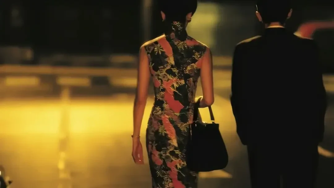Su Li-zhen and Chow Mo-wan walk side by side under amber street light in In the Mood for Love