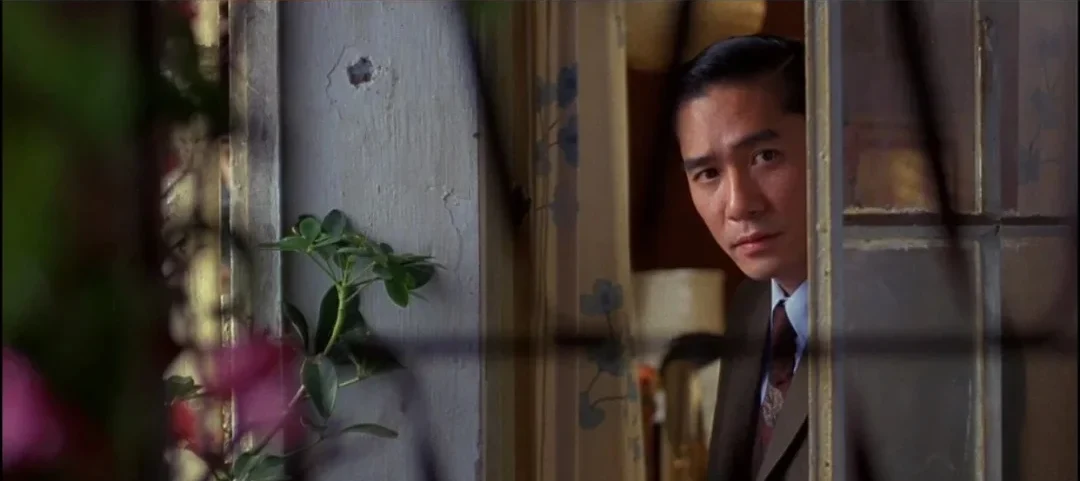 Chow watches through a weathered window frame in In the Mood for Love