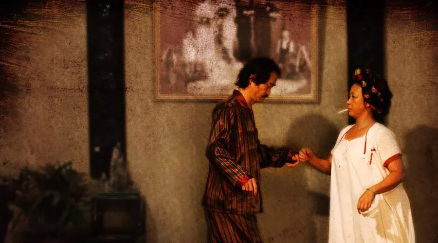 The Landlord and Landlady face one another in their deliberately ordinary Pig Sty Alley clothes