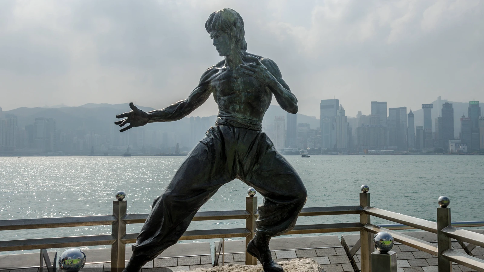 Bruce Lee memorial statue in a fighting stance on Hong Kong's Avenue of Stars with Victoria Harbour behind it