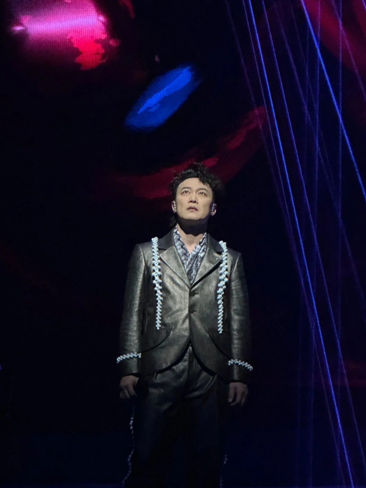 Eason Chan singing beneath a spotlight during the FEAR and DREAMS concert