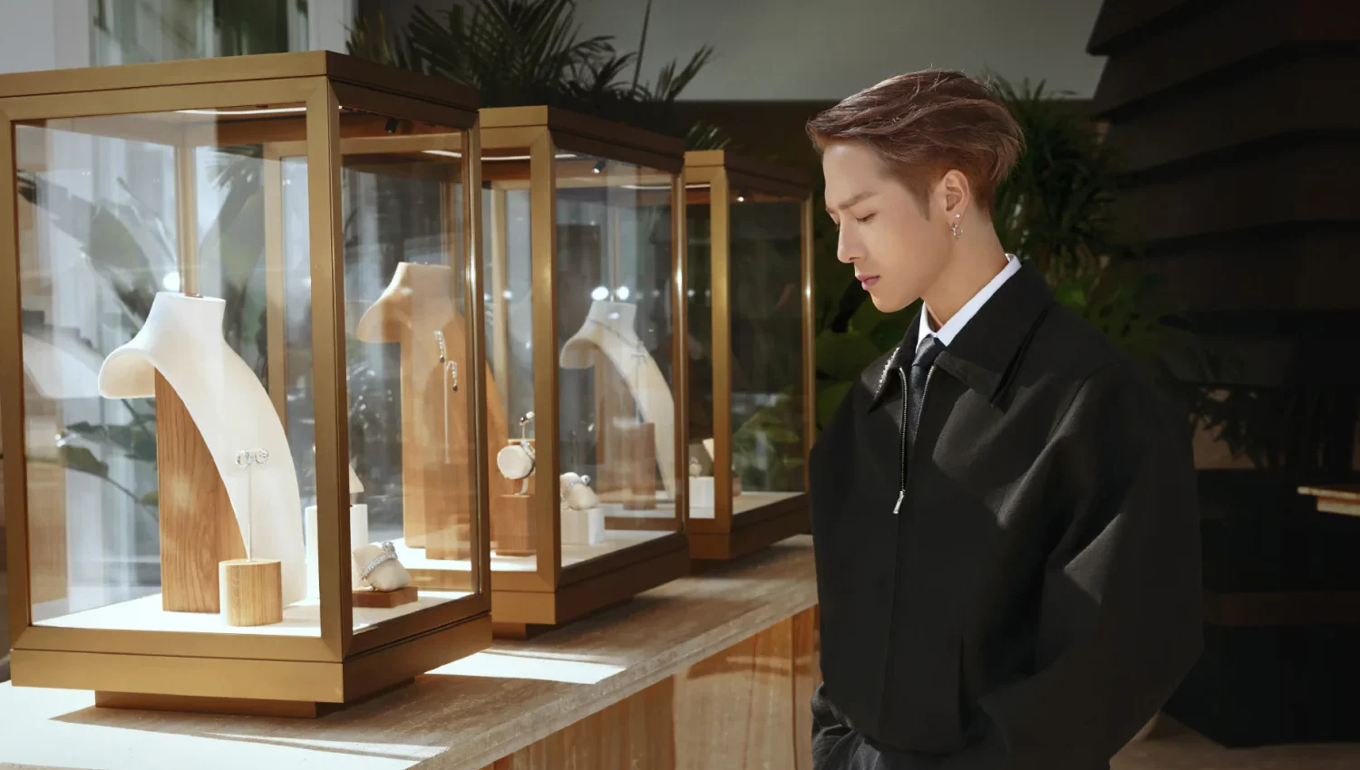 Jackson Wang in a black tailored look beside jewelry displays at a Dali brand event