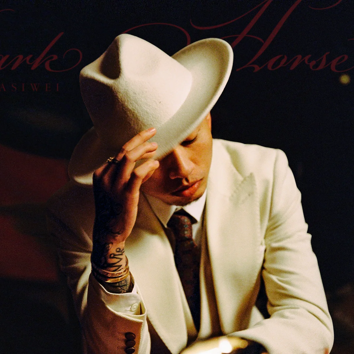 Masiwei wearing a white suit and hat in his official Apple Music artist portrait