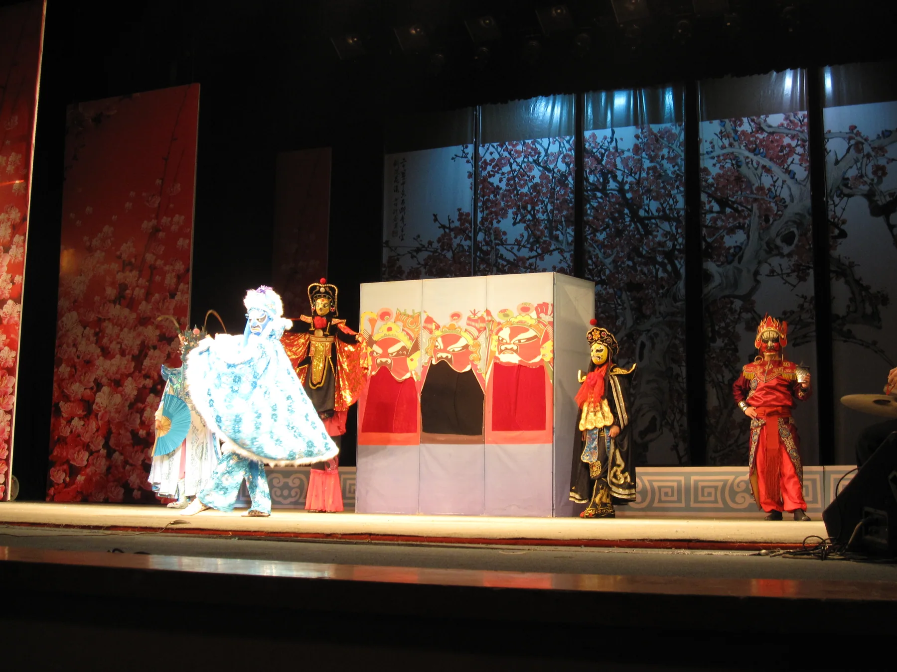 Several masked Sichuan Opera performers spread across a Chengdu stage