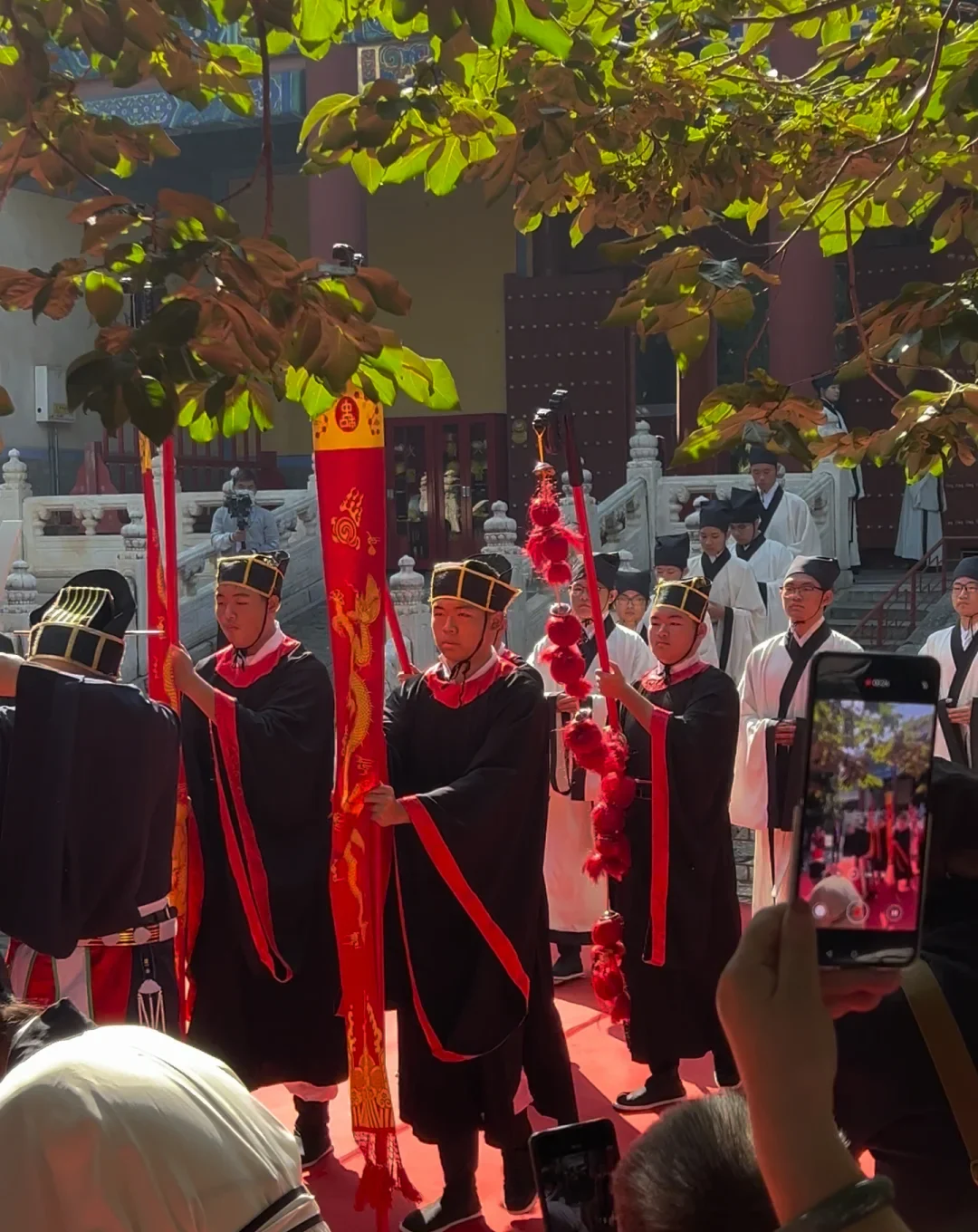 A contemporary Confucian ceremony performed in a temple courtyard while visitors record it on phones