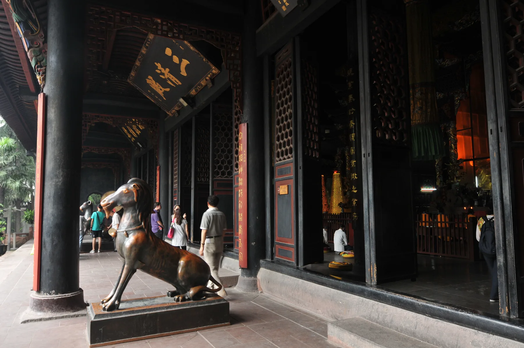 Visitors pass a bronze goat beside the incense hall at Qingyang Palace in Chengdu