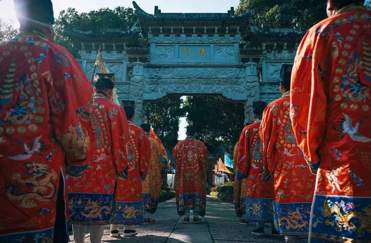 Visitors in embroidered Daoist ritual robes walking through a Tianshi Fu gate